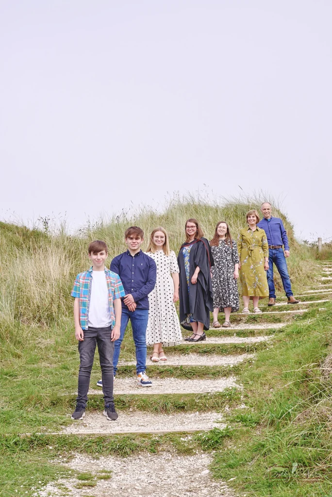 Coastal dune steps family portrait in Ballymoney with seven smiling relatives in casual summer outfits for an outdoor session